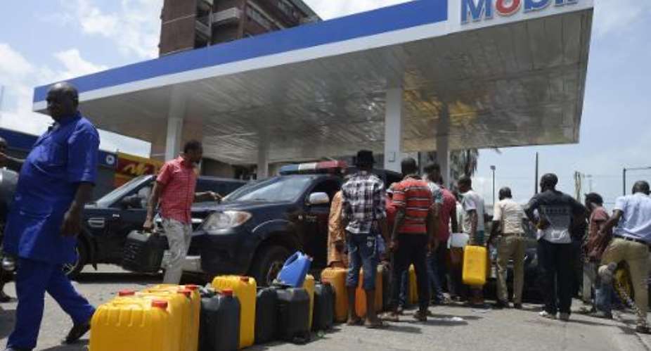 People queue with jerrycans to buy fuel at a Mobil filling station in Lagos on May 21, 2015.  By Pius Utomi Ekpei AFP