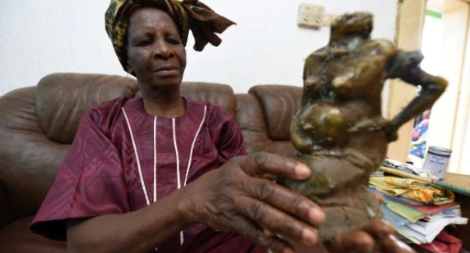 Nigerias first female bronze caster Princess Elizabeth Olowu, 77, holds her bronze sculpture in her living room in Benin City.  By Pius Utomi Ekpei (AFP)