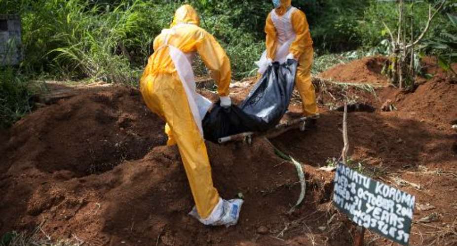 Funeral workers trained in the burial of Ebola victims lower a body into a grave at the Fing Tom cemetery in Freetown, Sierra Leone on October 10, 2014.  By Florian Plaucheur AFPFile