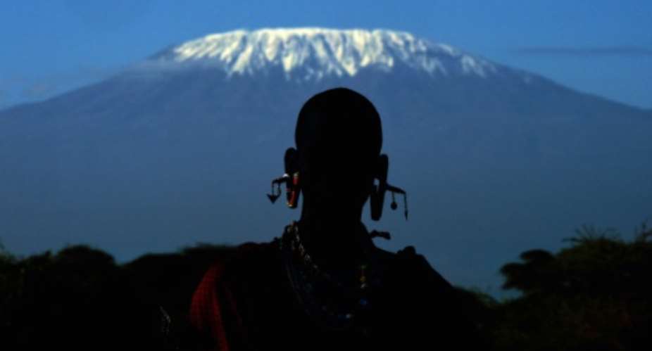 A Maasai man is silhouetted in front of Mount Kilimanjaro in Kimani on December 13, 2014.  By Carl de Souza AFPFile