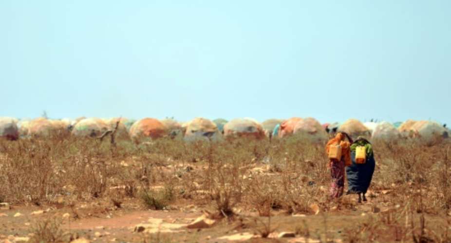 On March 14, 2017 women carrying jerrycans of water from a collection point set up by a UN aid agency walk towards a makeshift camp on the outskirts of Baidoa, Somalia, where thousands arrive daily after fleeing the parched countryside.  By TONY KARUMBA AFPFile