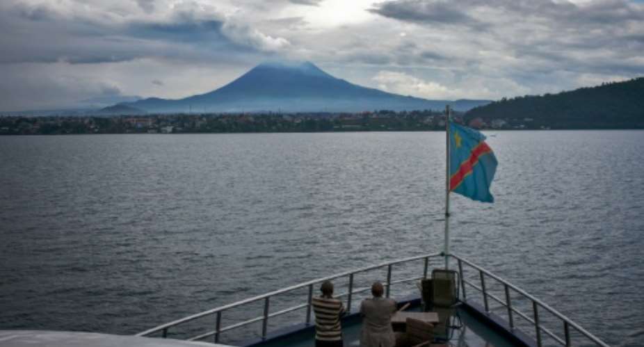Passengers stand at the bow of one of the ferries that ply Lake Kivu between Goma and Bukavu in the Democratic Republic of Congo to take in the view of the Nyiragongo Volcano on March 26, 2015.  By Federico Scoppa AFPFile