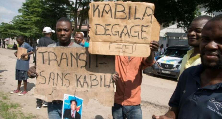Opposition supporters hold up placards reading 'Kabila - get lost' and 'Transition without Kabila' at a recent protest..  By JUNIOR KANNAH AFP