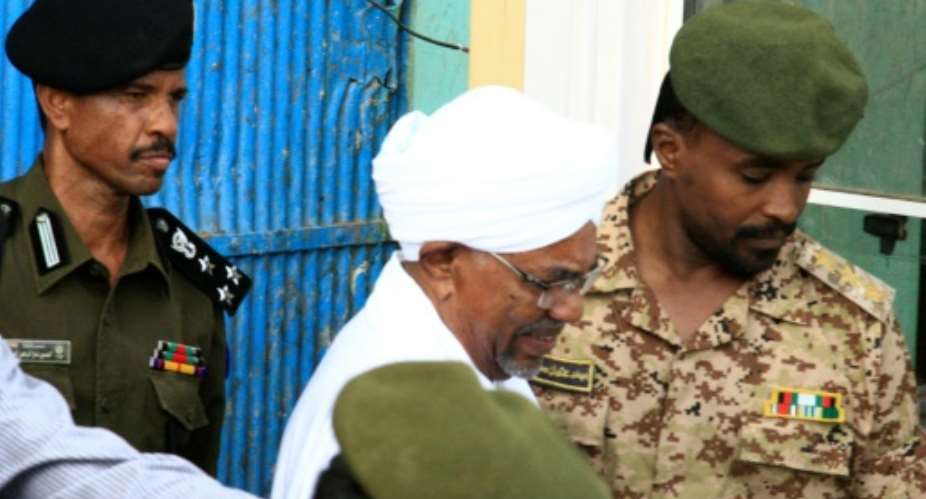 Ousted Sudanese leader Omar al-Bashir who appeared in court Monday for the start of his trial on corruption charges is seen in this June 2019 picture being escorted from the Kober prison to the prosecutor's office in North Khartoum.  By Ebrahim Hamid AFPFile