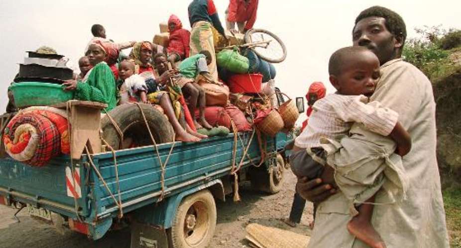 A file photo taken on July 12, 1994 shows a man carrying a young child as refugees flee the town of Kivumu as they fear the advance of the Rwandese Patriotic Front troops.  By Pascal Guyot AFPFile