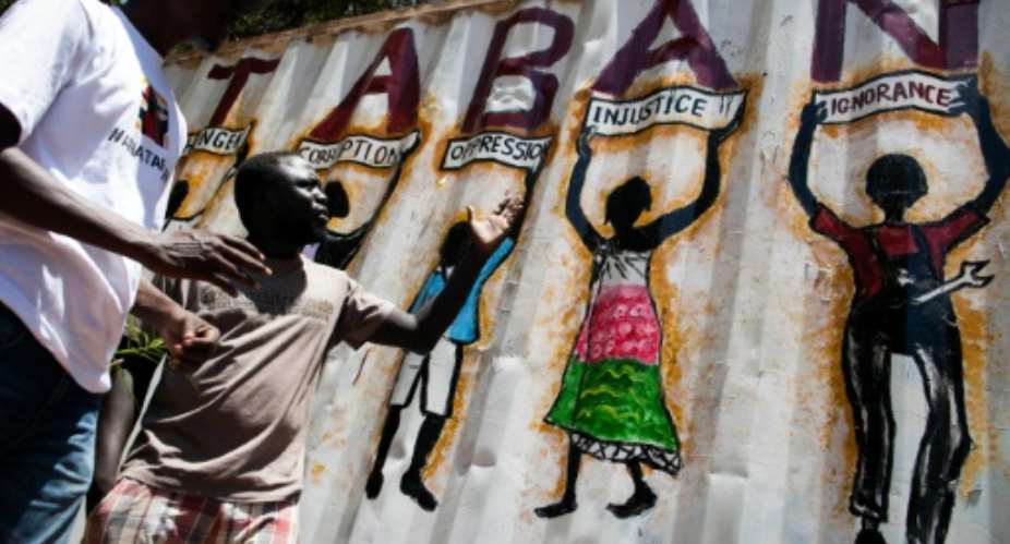 Painter Thomas  Dai L and musician James Aka, both  members of the new activist movement AnaTaban, talk in front of Thomas' latest graffiti in a street in Juba, South Sudan.  By Albert Gonzalez Farran AFPFile