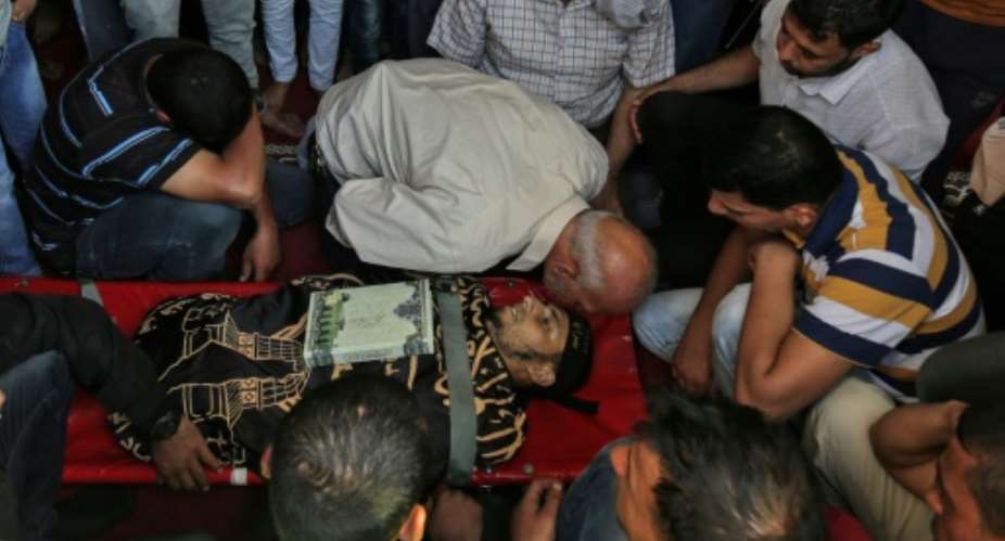 Palestinian mourners gather around the body of a man who was killed during a protest at the Israel-Gaza border on May 14, 2018, during his funeral at a mosque in Khan Yunis in the southern Gaza Strip.  By SAID KHATIB AFP