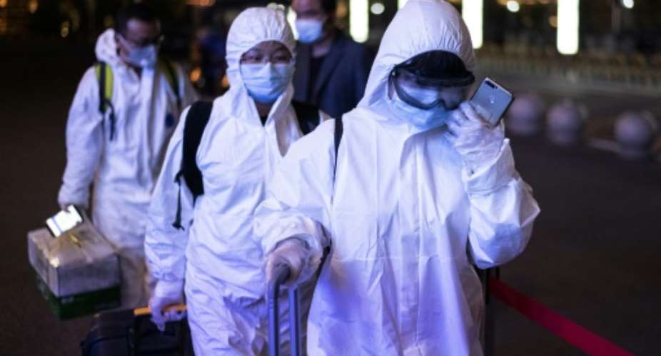 Passengers wear hazmat suits at a Wuhan railway station after a long lockdown was lifted.  By NOEL CELIS AFP