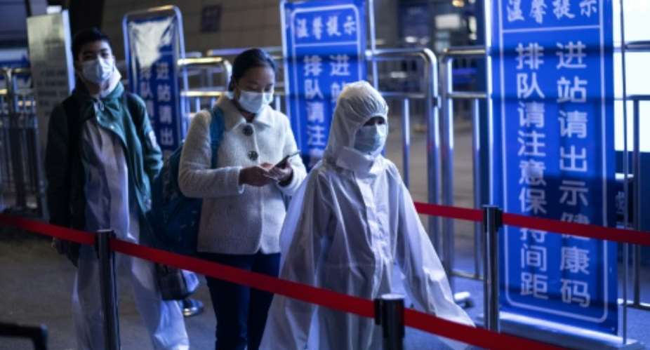 Passengers wear protective clothing as they arrive at the railway station in Wuhan after the authorities lifted a travel ban.  By NOEL CELIS AFP