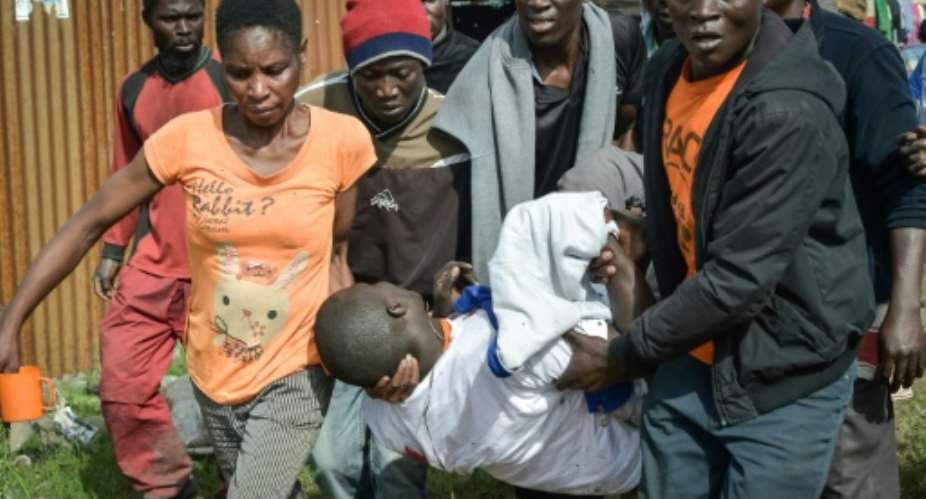 People carry the body of a man allegedly shot dead by police in Friday's clashes.  By SIMON MAINA AFP