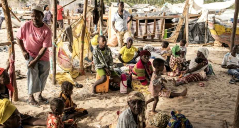 People gather under a makeshift displacement shelter as they arrive at Paquitequete beach in Pemba after fleeing Palma. More arrive on an almost daily basis..  By JOHN WESSELS AFP