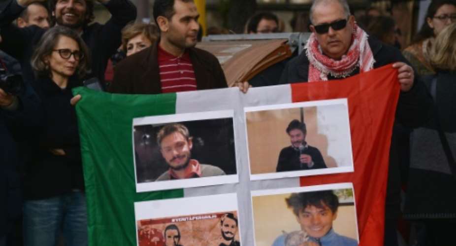 People hold an Italian flag with photos of student Giulio Regeni.  By Filippo Monteforte AFPFile