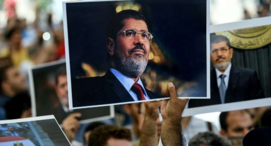 People hold up portraits of Egypt's former president Mohamed Morsi during a symbolic funeral ceremony at Fatih mosque in Istanbul.  By - AFP