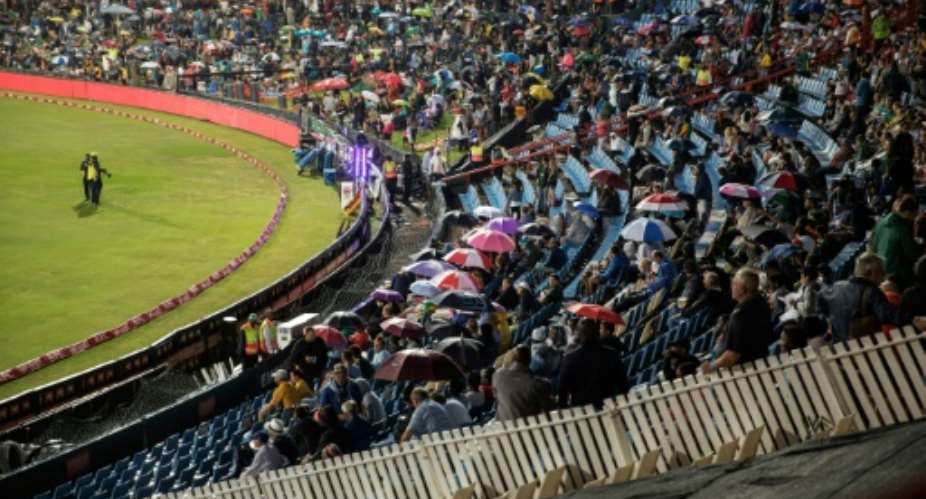 People hold up umbrellas as as they wait for start of the first match between South Africa and Sri Lanka on January 20, 2017 at Supersport park, which ended in a 126-5 victory for South Africa.  By Gianluigi Guerica AFP