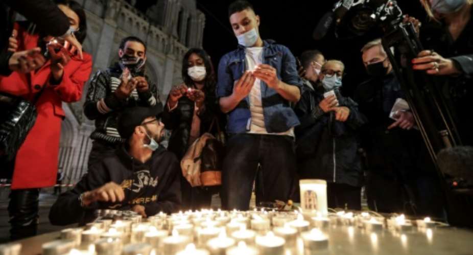People lights candle outside the Notre-Dame de l'Assomption Basilica in Nice in tribute to the three victims of a knife rampage, which France's president called an 'Islamist terrorist attack'.  By Valery HACHE AFP