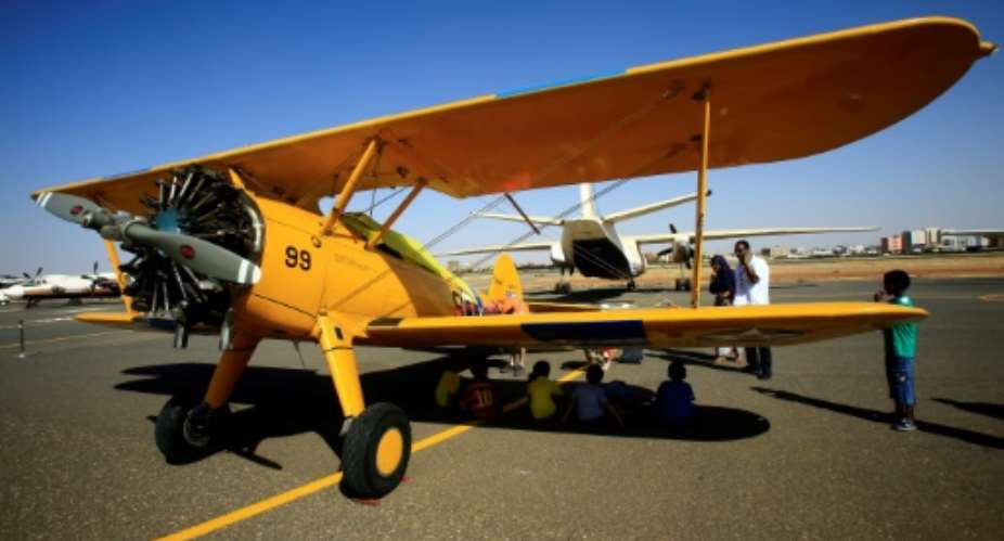 People look at a vintage Boeing Stearman Model 75 biplane as it sits on the runway at Khartoum airport in Khartoum, Sudan during the Vintage Air Rally VAR on November 20, 2016.  By Ashraf Shazly AFPFile