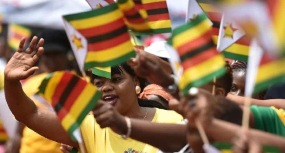 People react as Zimbabwe's new President Emmerson Mnangagwa is officially sworn-in during a ceremony in Harare.  By TONY KARUMBA AFP