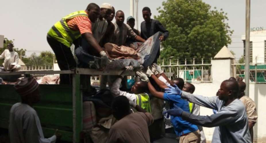 People unload from a truck to a morgue the bodies of victims in Bama, Borno State, northeastern Nigeria, on April 22, 2018, following twin suicide blasts inside of a mosque.  By AUDU MARTE AFP