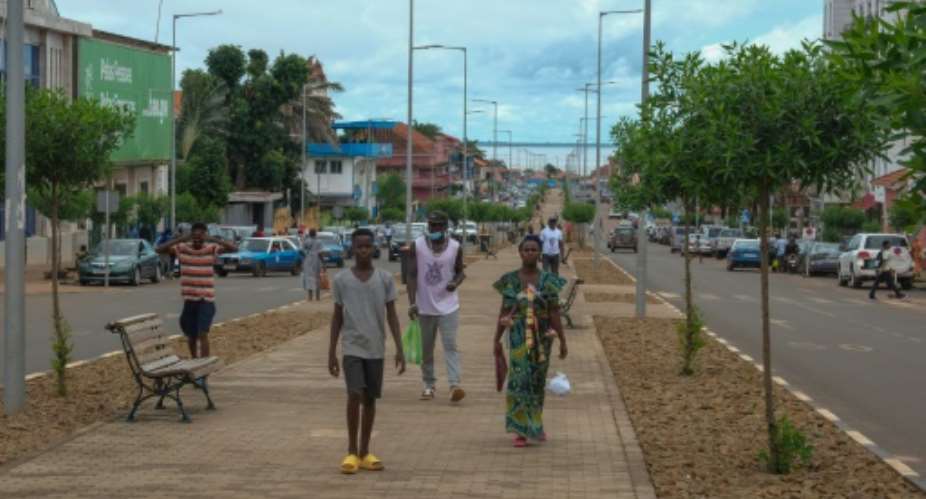 People walk down Amilcar Cabral Avenue in Guinea-Bissaus capital of Bissau in September 2024.  By Ricci Shryock (AFP/File)