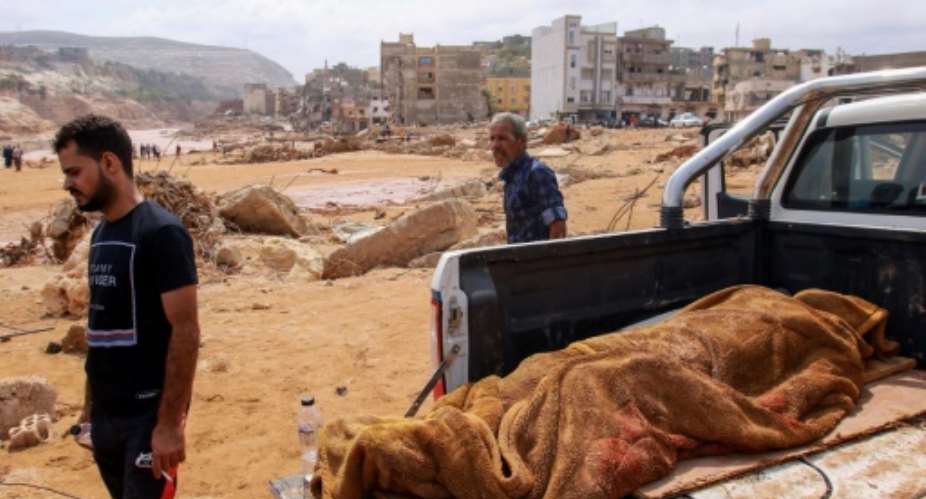 People walk past the body of a victim from the flood which devastated Derna, eastern Libya.  By - AFPFile