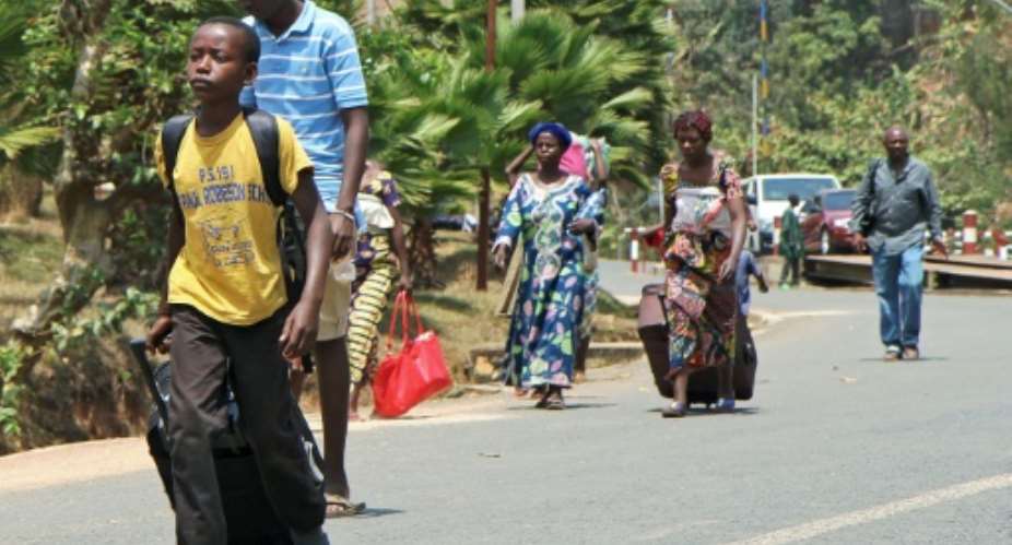 People walk towards buses in Akanyaru on the Rwandan side after crossing the border from Burundi.  By Stephanie Aglietti AFP