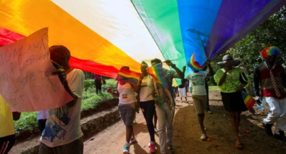 People walk under a giant rainbow flag at the Gay Pride Parade in the Ugandan city of Entebbe in 2015.  By ISAAC KASAMANI AFPFile