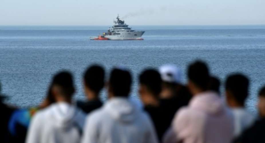 People watch as a naval ship arrives at the scene of a helicopter crash in the Mediterranean Sea off the coast of Algeria on Wednesday.  By Ryad KRAMDI AFP