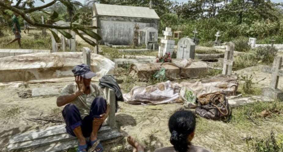 People watch over the bodies of relatives after the cyclone caused waves that ripped open graves at a cemetery in eastern Madagascar.  By Laure Verneau AFP