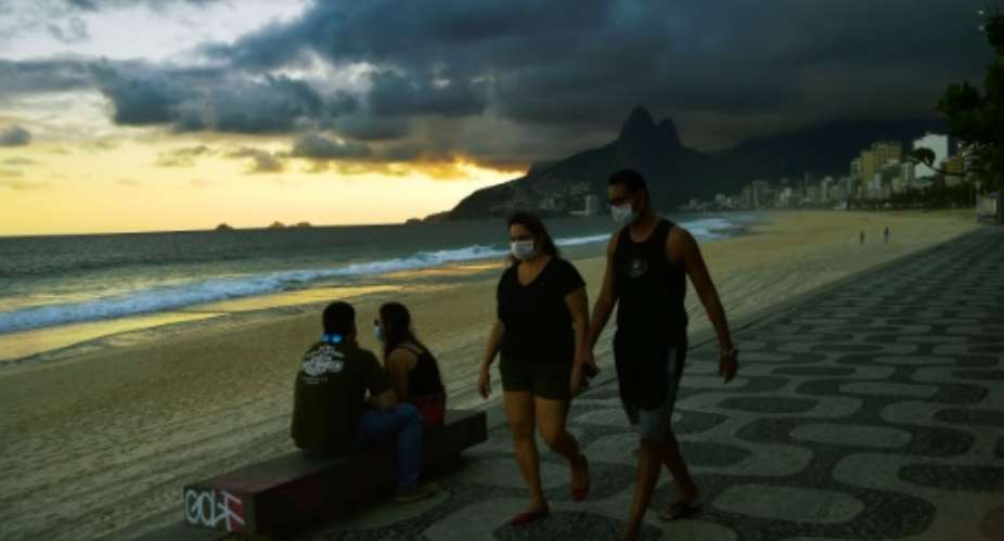 People wear face masks onIpanema Beach in Rio de Janeiro on May 19, 2020, as Brazil recorded its highest yet daily death toll from COVID-19.  By Carl DE SOUZA AFP
