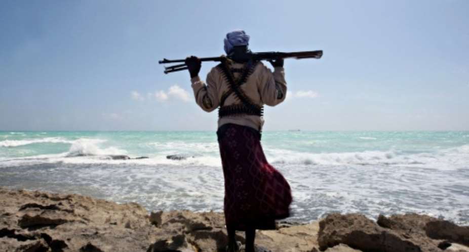 An armed Somali pirate stands on the shore near Hobyo town in 2010 looking at the hijacked Greek cargo ship MV Filitsa anchored off the coast.  By Mohamed Dahir AFPFile