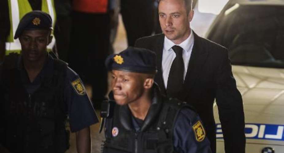 South African Paralympian athlete Oscar Pistorius centre is escorted by south african policemen upon his arrival at the High Court in Pretoria on October 21, 2014.  By Gianluigi Guercia AFPFile