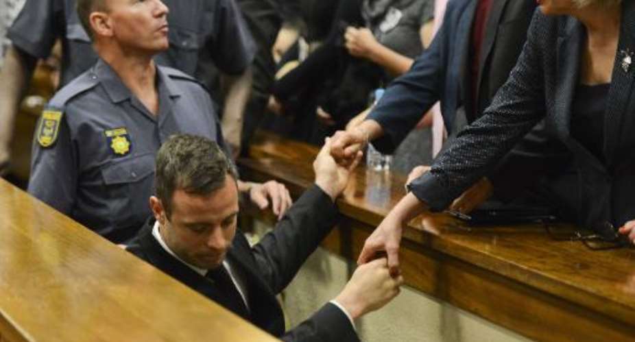 Oscar Pistorius holds the hands of family members as he is taken down to the holding cells after being sentenced to five years imprisonment at the High Court in Pretoria, on October 21, 2014.  By Herman Verwey PoolAFP