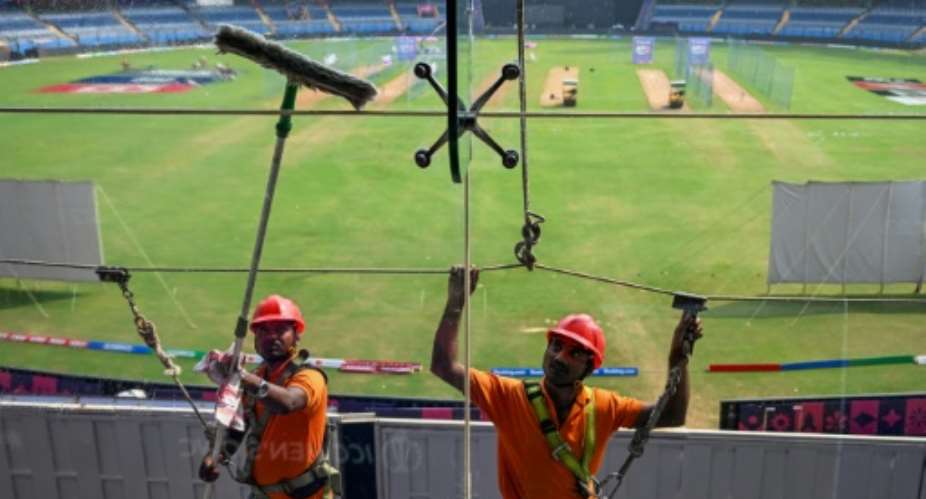 Point of view: Workers clean glass outside the media box at the Wankhede Stadium in Mumbai on Monday.  By Punit PARANJPE AFP
