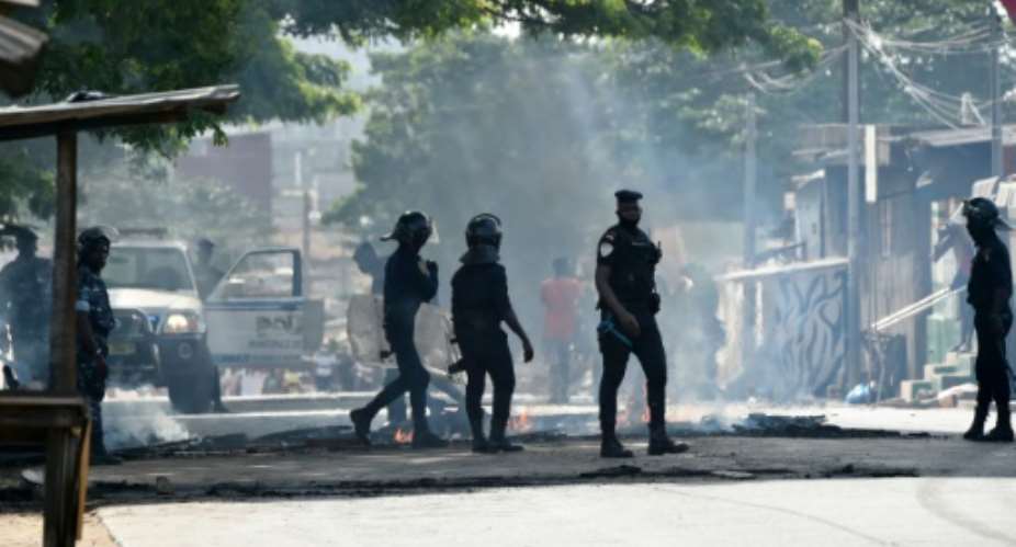 Police clear debris that was placed in the road by young demonstrators during protests against President Alassane Ouattara's run for a third term, in the Yopougon neighbourhood of Abidjan on August 13, 2020.  By SIA KAMBOU AFPFile
