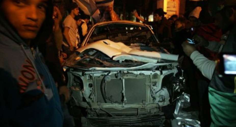 Libyans look at a car after an improvised bomb hit a police patrol vehicle late on January 14, 2013, in Benghazi.  By Abdullah Doma (AFP/File)