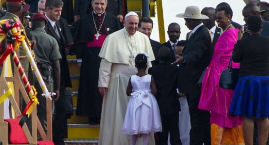 Pope Francis is greeted a young girl and Uganda President Yoweri Museveni upon his arrival in Entebbe, on November 27, 2015.  By Isaac Kasamani AFP