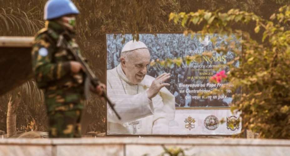A UN Multidimensional Integrated Stabilization Mission in the Central African Republic MINUSCA soldier stands guard near a billboard announcing the visit of Pope Francis outside the Barthelemy Boganda stadium in Bangui.  By Gianluigi Guercia AFP