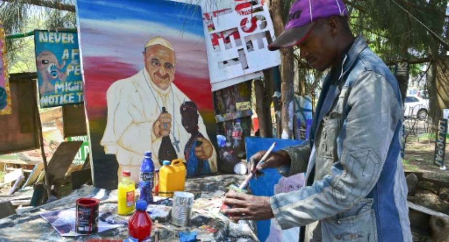 A street artist mixes paint as he works on a painting of Pope Francis in Nairobi, on November 20, 2015.  By Kevin Midigo AFPFile