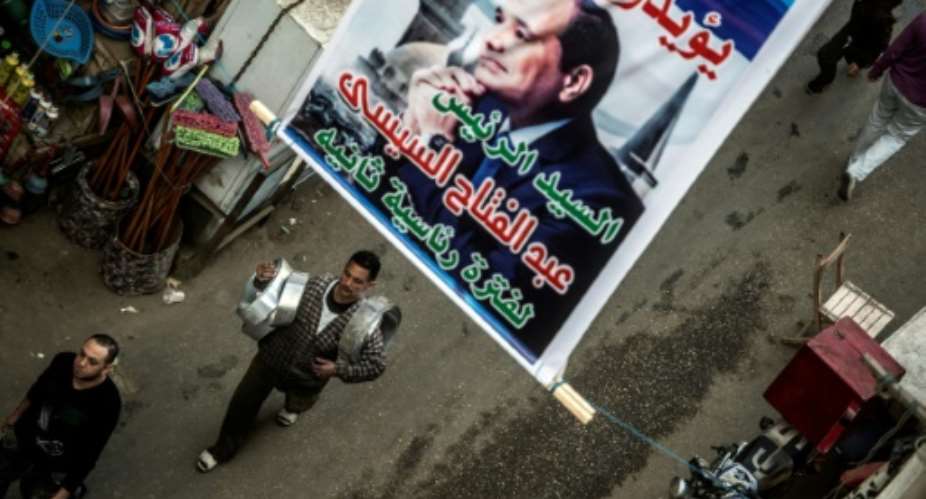 Posters supporting Egyptian President Abdel Fattah al-Sisi hang in  downtown Cairo ahead of an election that looks certain to hand him a second term in office.  By KHALED DESOUKI AFP