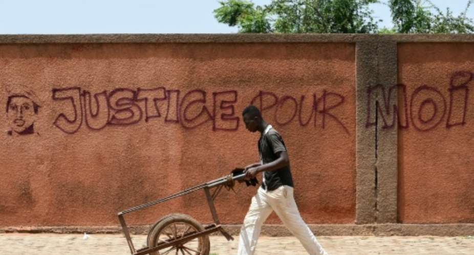 A man wheels a cart past a wall with graffiti reading Justice for me in Ouagadougou on October 1, 2015.  By Sia Kambou AFPFile