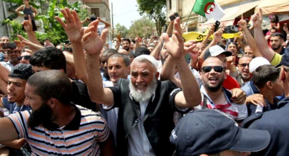 Protesters demonstrate as Algeria's former prime minister Abdelmalek Sellal is driven to custody in Algiers on June 13.  By - AFP