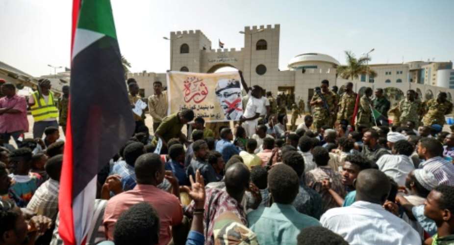 Protesters gather in front of soldiers during a rally demanding a civilian body to lead the transition to democracy, outside the army headquarters in the Sudanese capital Khartoum on April 12, 2019.  By MOHAMMED HEMMEAIDA AFP