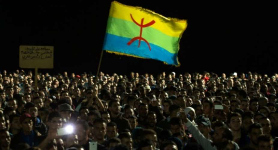 Protesters hold the Berber flag as they shout slogans in Al Hoceima, Morocco on October 30, 2016, following the death of fishmonger Mouhcine Fikri, who was crushed to death on October 28 in a rubbish truck.  By Fadel Senna AFP