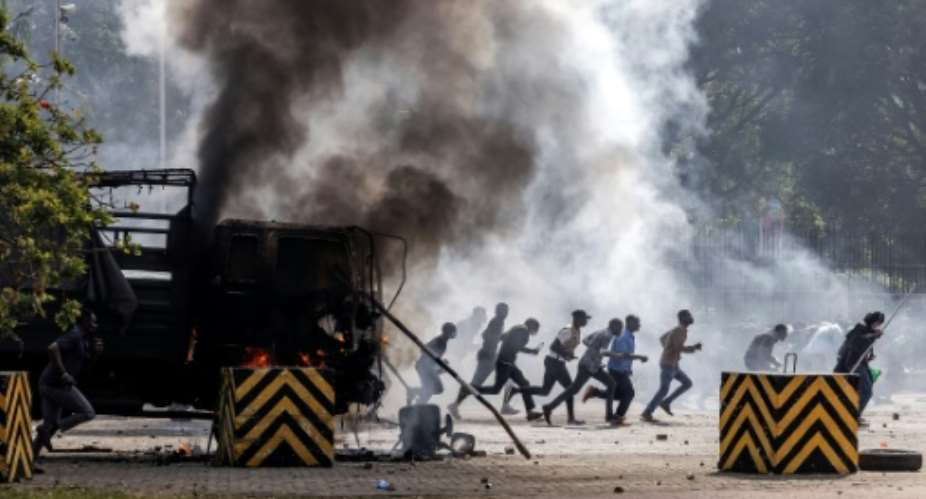 Protesters run to take cover during unrest outside the Kenyan parliament.  By LUIS TATO (AFP)