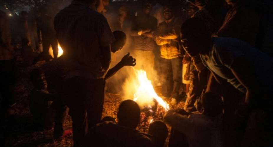 Protesters stand around a fire at a vigil against the result of the May 21 presidential vote in Lilongwe on July 4, 2019.Malawi's re-elected President Peter Mutharika has condemned the protests.  By AMOS GUMULIRA AFP