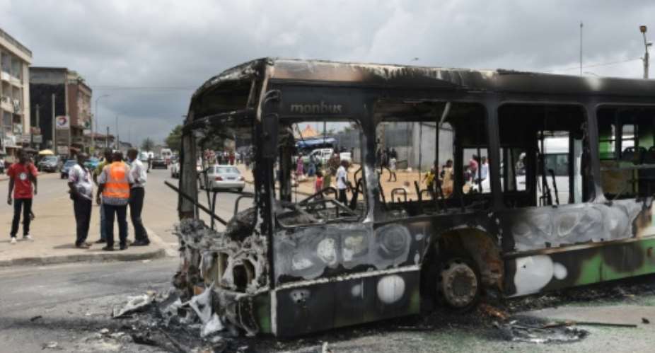 Protesters torched a bus in a working-class district of Abidjan.  By SIA KAMBOU AFP