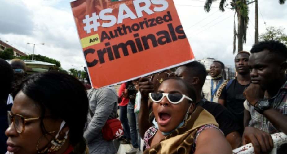 Protestors carry a placard reading Special Anti-Robbery Squad SARS Are Authorised Criminals.  By PIUS UTOMI EKPEI AFP