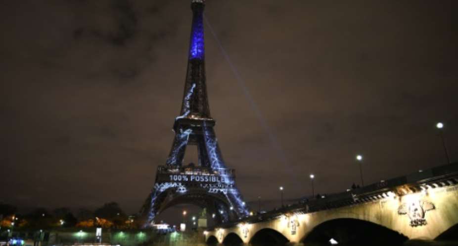 The Eiffel Tower is illuminated with messages against global warming during the first day of the United Nations climate conference in Paris on November 30, 2015.  By Stephane De Sakutin AFP
