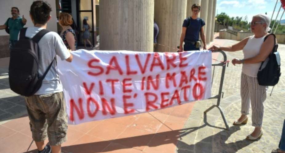 Rackete's supporters hold a banner reading 'Saving lives at sea is not a crime' outside the courthouse.  By Andreas SOLARO AFP