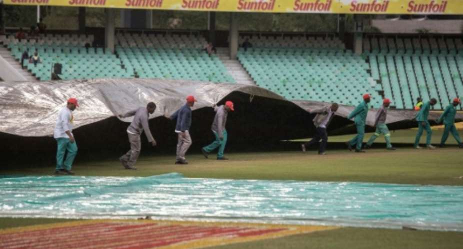 Workers pull a cover onto the pitch as rain delays start of play on the second day of the first Test Match between South Africa and New Zealand at the Sahara stadium in Durban on August 20, 2016.  By Gianluigi Guercia AFP